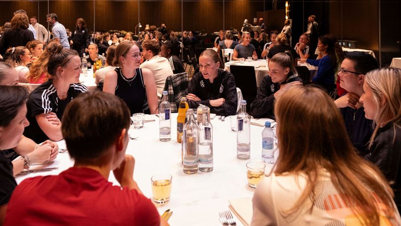 Foto: Yuliia Perekopaiko/DFB / Olympia macht es möglich: Die Gewehrschützinnen wie Anna Janßen und Lisa Müller sitzen mit den Kickerinnen des DFB am Tisch und tauschen sich aus.